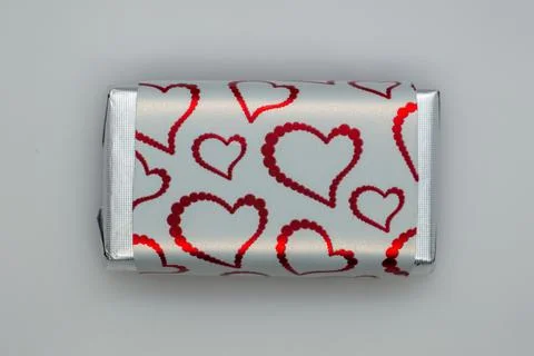 Chocolate candy wrapper in the form of a heart on a gray background. Stock Photos