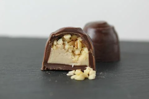 Chocolate case candy in section with praline peanuts crushed on a gray backgr Stock Photos