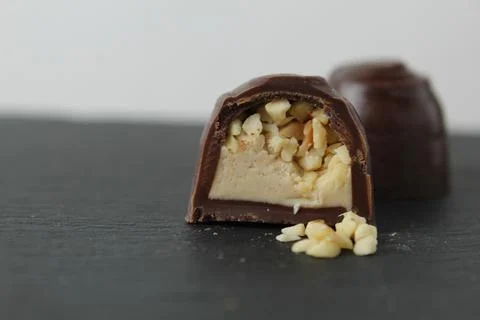 Chocolate case candy in section with praline peanuts crushed on a gray backgr Stock Photos