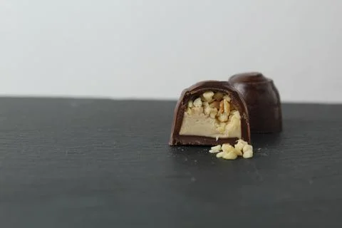 Chocolate case candy in section with praline peanuts crushed on a gray backgr Stock Photos