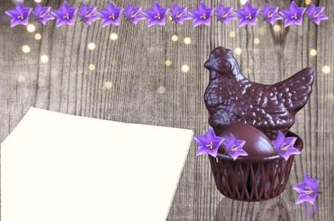 Chocolate chicken with Easter eggs and flowers on a wooden background. A blan 写真素材