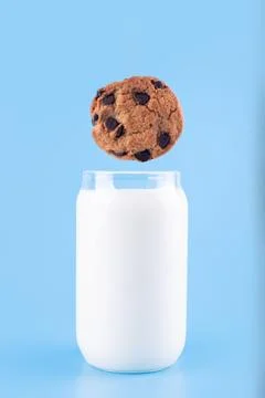 The chocolate chip cookie biscuit levitates in the air over a glass of milk.. Stock Photos