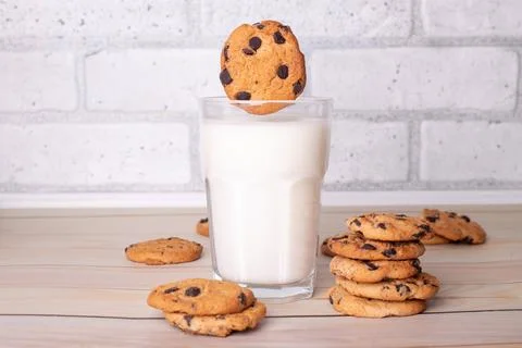 The chocolate chip cookie biscuit levitates in the air over a glass of milk.. Stock Photos