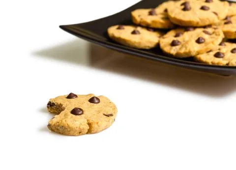 Chocolate chip cookie with a bite and pile of cookies in a plate on the backg Stock Photos