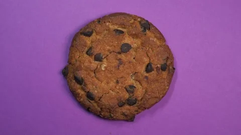Chocolate chip cookie close-up, macro shot, slowly spinning on a rotating purple Stock Footage 89307930