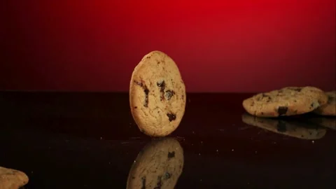 Chocolate chip cookie spins on a dark reflective surface Stock Footage 327631820