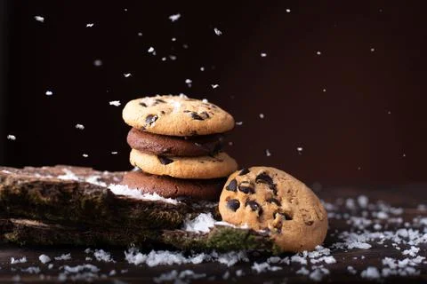 Chocolate chip cookie tower under the snow on a dark wooden background. Foto stock