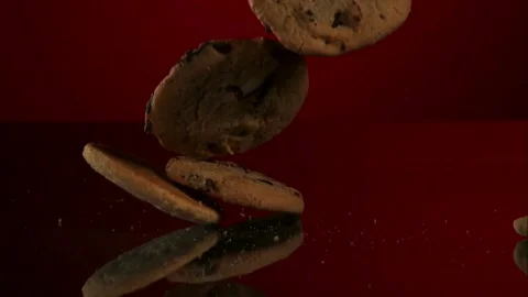 Chocolate chip cookies fall on a dark reflective surface Video stock 327513138
