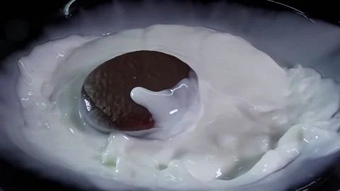 Chocolate chip cookies slowly fall into a bowl filled with creamy milk, creating Stock Footage 280683531