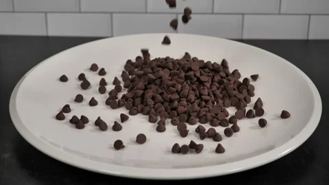 Chocolate chips are poured onto a platter in slow motion. Stock Footage 140267537