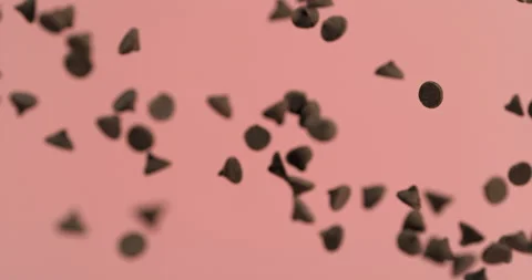 Chocolate chips fly into air in super slow motion on pink background Video stock 249560429