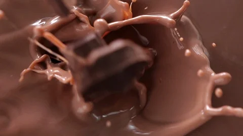Chocolate chunks fall into chocolate milk - top view, slow motion Stock Footage 105718531