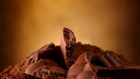 Chocolate chunks heap and cocoa rotate on plate - close up Video stock 104464284