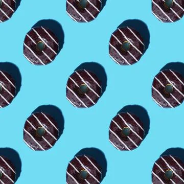Chocolate-coated donut pattern with white stripes on a blue background Stock Photos