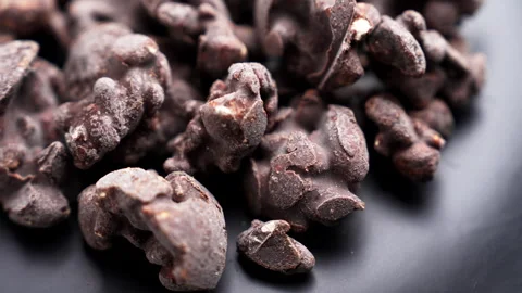 Chocolate coated nuts on a dark ceramic background. Rotation Stock Footage 345416353
