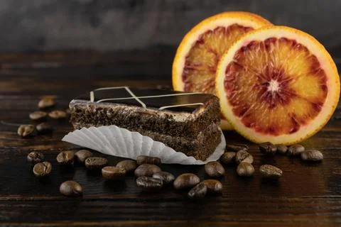 Chocolate-coated sponge cake with two slices of red orange and a scattering o Foto stock