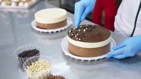 Chocolate, cocoa and milk dragee candies are put on top of the cake. Tasty cakes Stock Footage 174875162