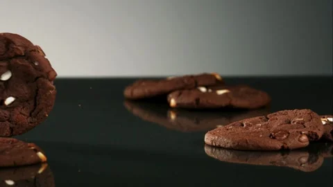 Chocolate cookie falling on dark reflective surface Video stock 327181145