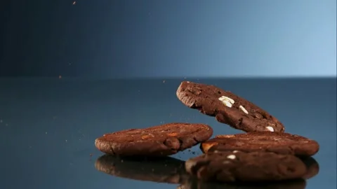 Chocolate cookies bouncing on blue reflective surface Stock Footage 327122313