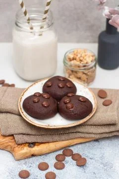 Chocolate cookies with choco drops on white plate, and glass of milk Stock Photos
