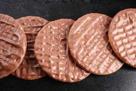 Chocolate cookies lined up on a black surface Stock Photos