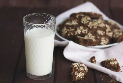 Chocolate cookies with sesame seeds in a vintage plate and the glass of milk  Stock Photos