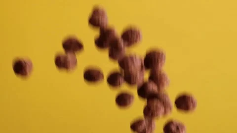 Chocolate corn cereal balls moving up and down on a yellow background. Stock Footage 131381706