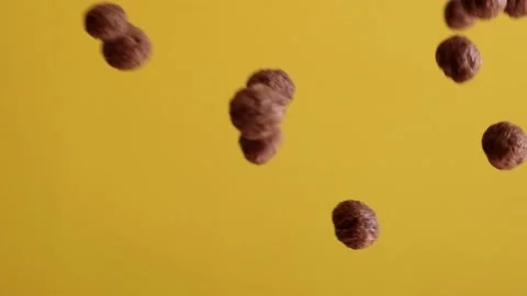 Chocolate corn cereal balls moving up and down on a yellow background. Stock Footage 131381742