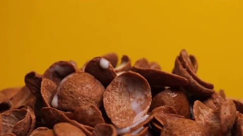 Chocolate corn flakes on a yellow background, rotation. Sweet crispy breakfast p Stock Footage 238899723
