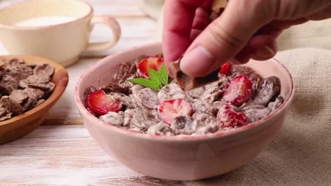 Chocolate cornflakes with milk decorating with almonds. Side view, close up. Stock Footage 135042506