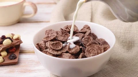 Chocolate cornflakes poured with milk in ceramic bowl. Side view, close up. Stock Footage 135042579