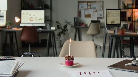 Chocolate Cupcake with Burning Candle on Small Plate near Documents and Laptop Stock Footage 331536570