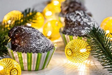 Chocolate cupcake with Christmas tree branches and a luminous garland Stock Photos