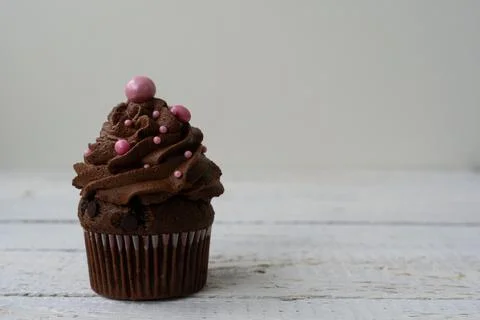 Chocolate cupcake with decorative ball. Rustic wood background Stock Photos