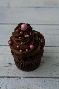 Chocolate cupcake with decorative ball. Rustic wood background Stock Photos