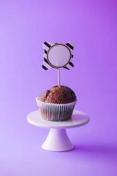 Chocolate cupcake with empty topper label, purple background Stock Photos