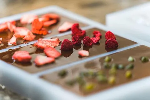 Chocolate decorating process. Home-made chocolate bars with raspberries Stock Photos