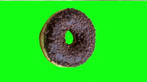 Chocolate donut appears on a green background and then spins around 360 degre Stock Footage