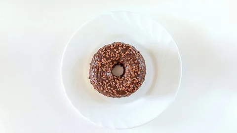 Chocolate donut rotating, stop motion, animation on white, from above, flatlay Stock Footage 124461771