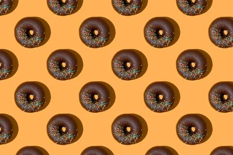 Chocolate donuts pattern on orange background. Top view, flat lay Foto stock