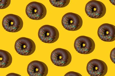 Chocolate donuts pattern on yellow background. Top view, flat lay Foto stock