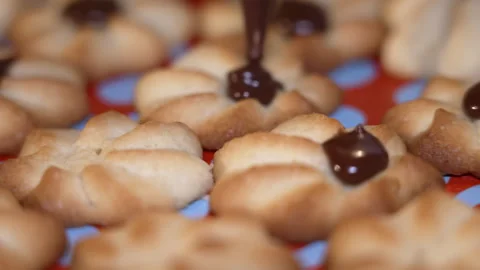 Chocolate drizzle applied to freshly baked cookies on colorful baking mat Vídeos de archivo 345677255