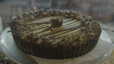 Chocolate Drizzled Pie with Toppings in Bakery Display Case, Sydney Cafe Stock Footage 345668760