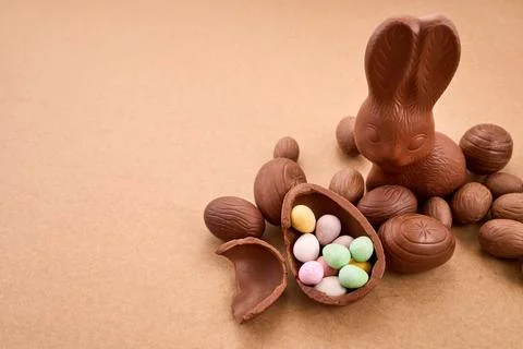 Chocolate easter bunny with candy eggs on brown background Stock Photos