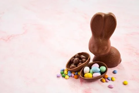 Chocolate easter bunny with candy eggs on pink marble 스톡 사진