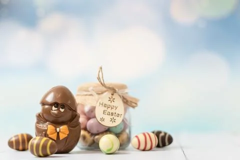 Chocolate easter chicken and a jar with eggs on a white wooden table. Foto stock