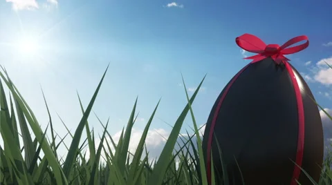 Chocolate Easter Egg with Red Ribbon in a Green Grass with Flowing Clouds Stock Footage 47947499