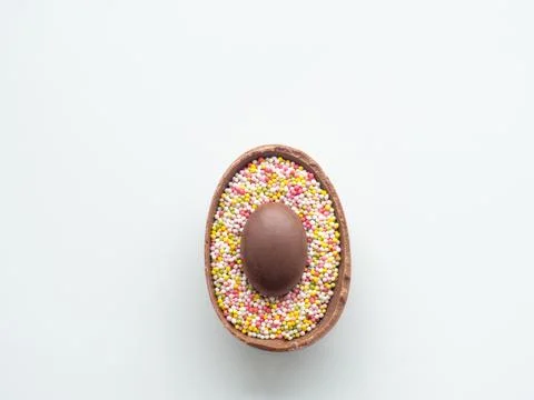 Chocolate easter egg with sweet sprinkles on white background Stock Photos