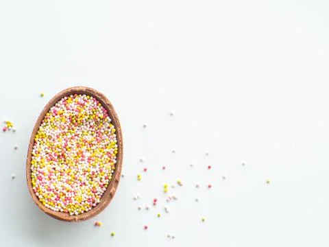 Chocolate easter egg with sweet sprinkles on white background Stock Photos