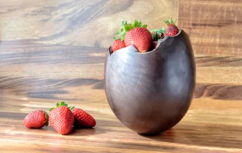 Chocolate Easter egg with the top broken off filled with strawberry Stock Photos